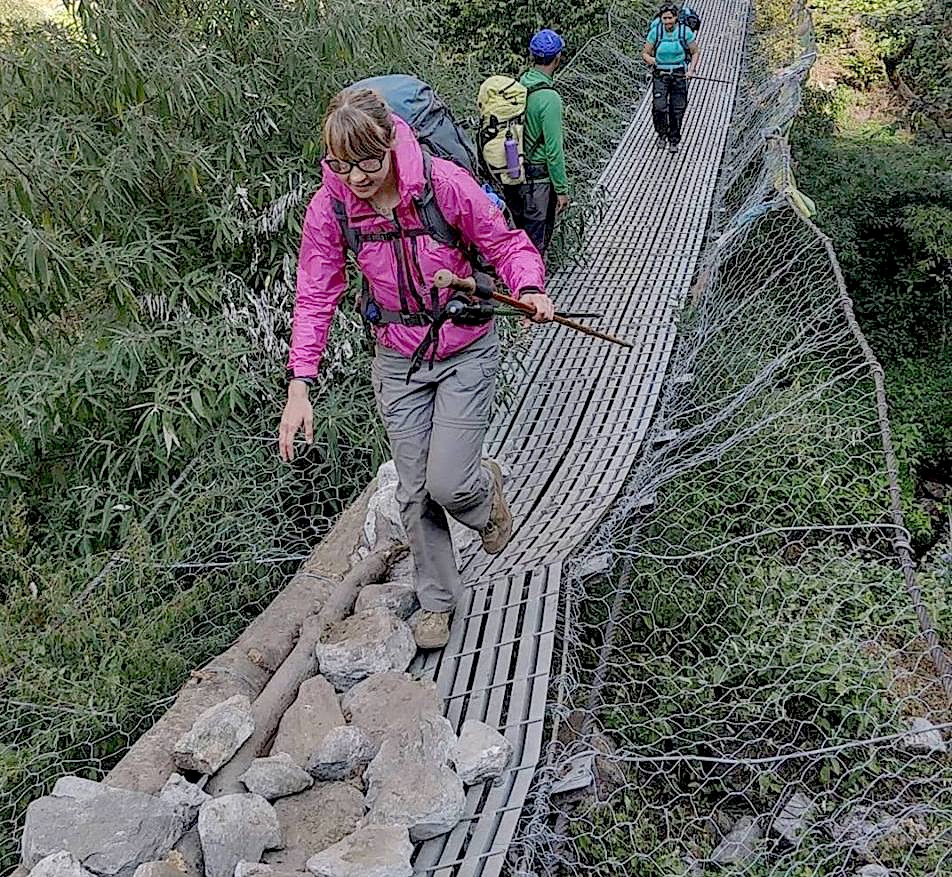 hiker crossing a suspension bridge in Nepal